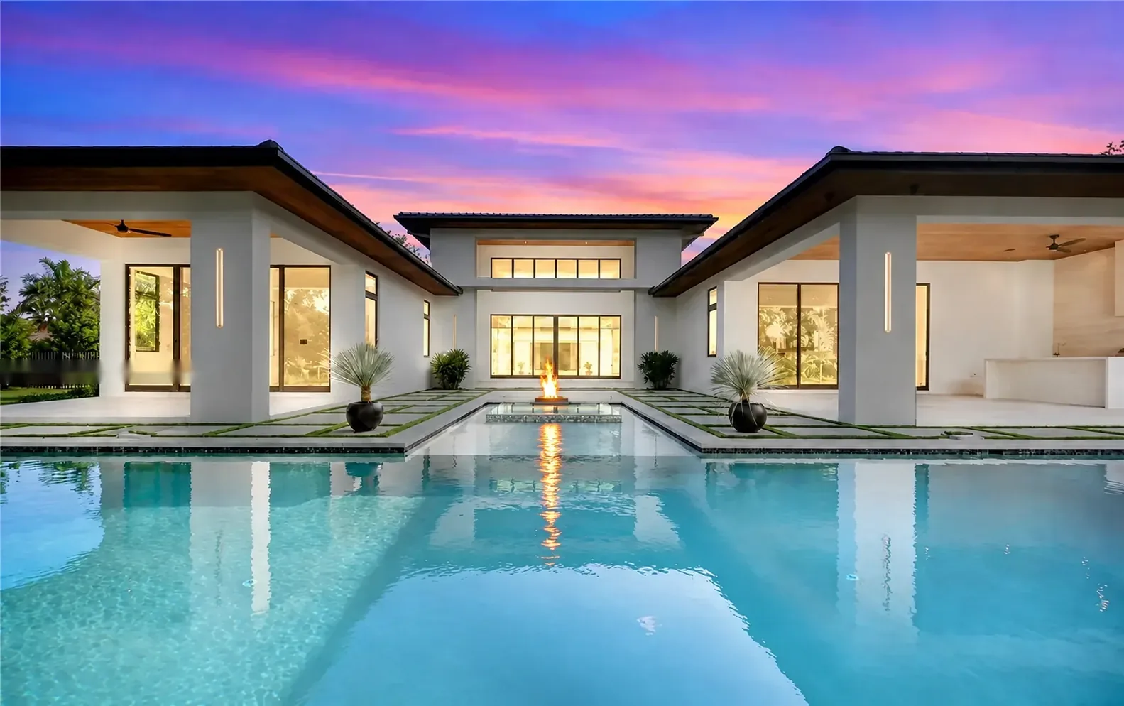 Pool at sunset with lit interiors beyond